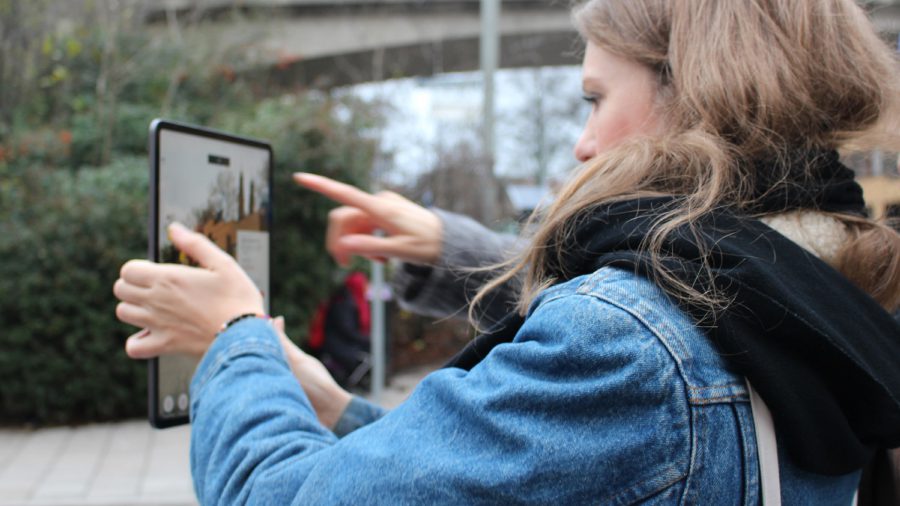 En person står håller en mobiltelefon i handen och pekar på skrämen