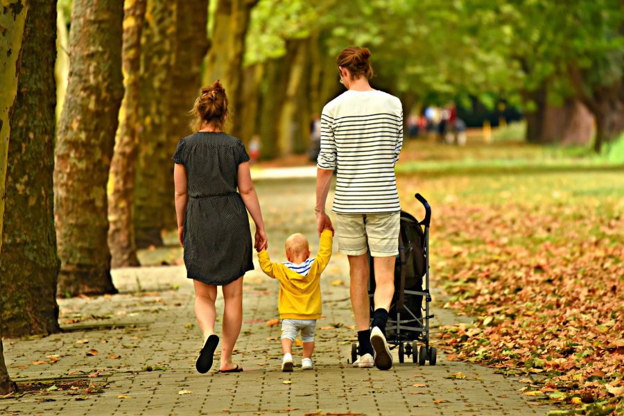 Två vuxna och ett barn går på en gångväg