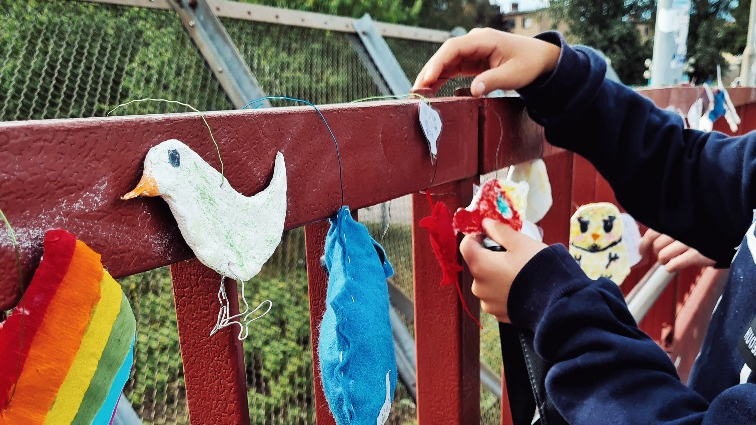 Ett barns händer sätter upp färgglada figurer på en bro