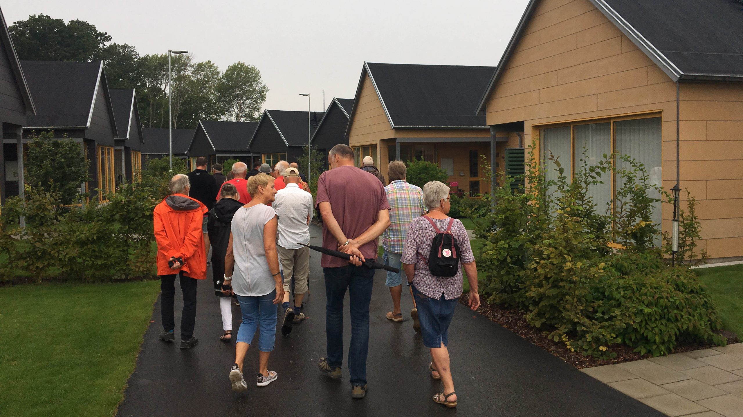 En grupp människor går omkring och tittar på hus, husen är färgglada