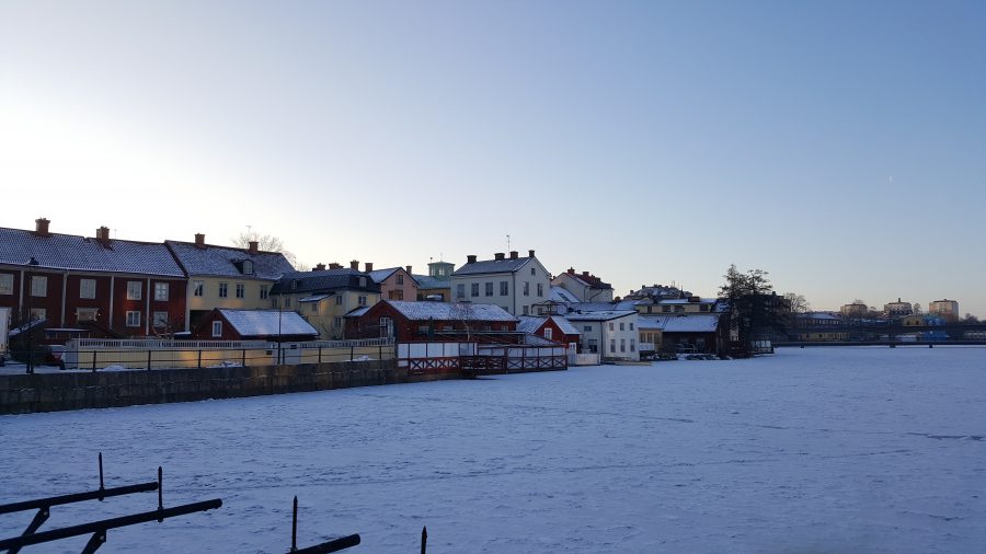 Ett snötäckt fält med bebyggelse i bakgrunden