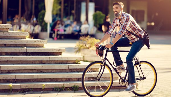 En man cyklar i en solig stadsmiljö