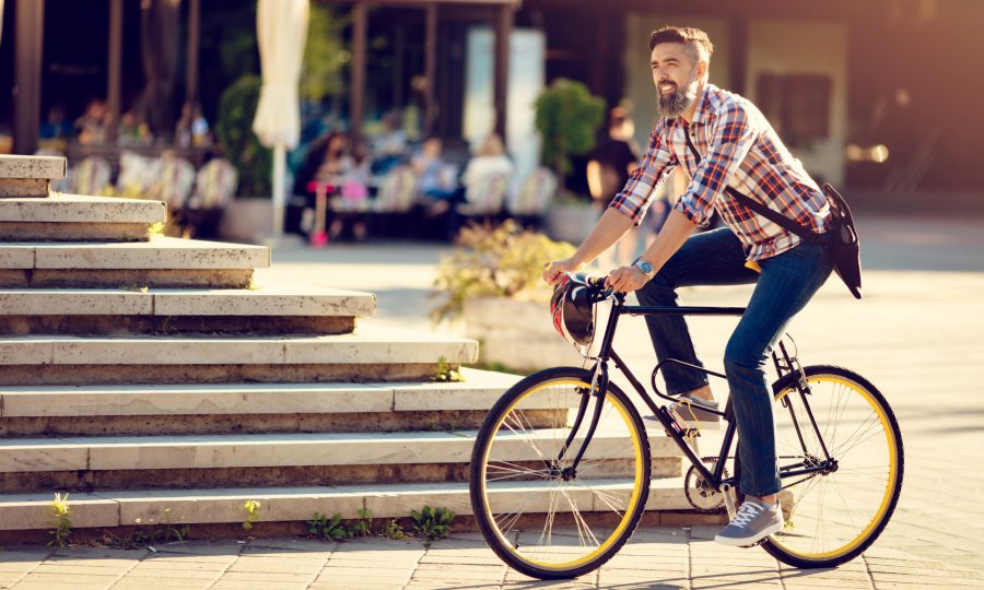 En man cyklar i en solig stadsmiljö