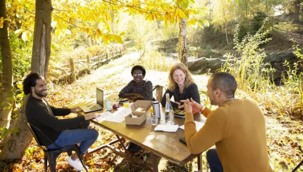 Fem strategier utvalda för att jobba med hållbar urban utveckling. Glada människor sitter vid ett bord i solen.