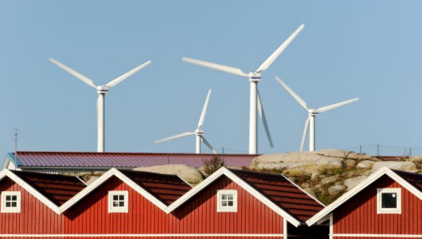 Klimatneutrala och socialt hållbara kommuner 2024. Foto på små röda hus med vindkraftverk i bakgrunden.
