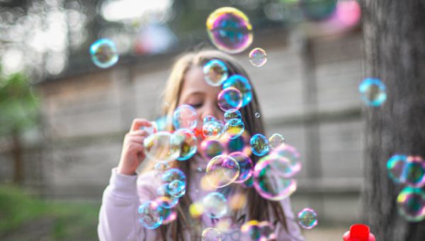 Utlysning: Accelererad klimatomställning i städer. Foto på barn med såpbubblor i olika färger.
