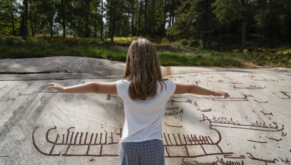 299 miljoner till kulturmiljövård. Foto på barn framför hällristning.