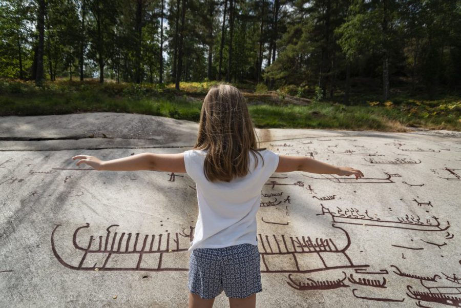 299 miljoner till kulturmiljövård. Foto på barn framför hällristning.