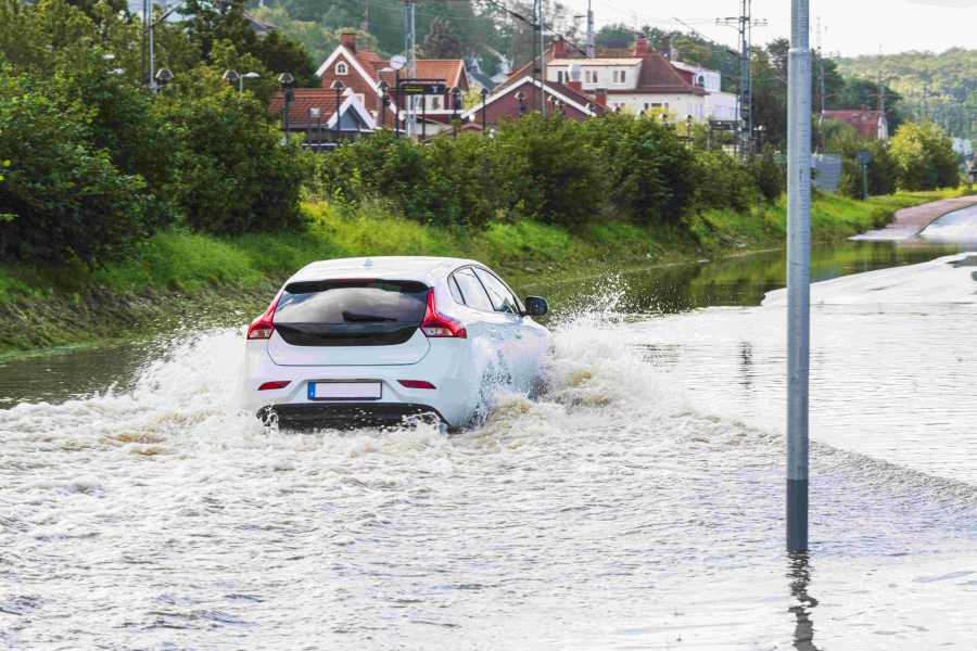 Kartläggning för reglering av vattenflöden. Bil åker på en vattenfylld väg.