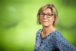 Porträtt av kvinna med glasögon, blå blus och ljus pageklippt hår.