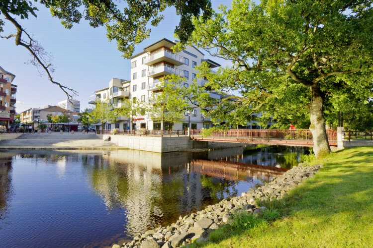 Flerbostadshus vid vatten och grönområde.